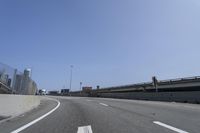 a person riding a motorcycle along a road next to a bridge with buildings behind them