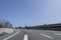 a person riding a motorcycle along a road next to a bridge with buildings behind them