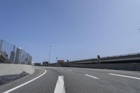 a person riding a motorcycle along a road next to a bridge with buildings behind them