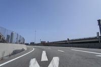 a person riding a motorcycle along a road next to a bridge with buildings behind them