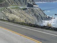 a motorcycle is riding down the coastal highway on a sunny day while a person on a bike stands at the corner