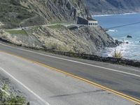 a motorcycle is riding down the coastal highway on a sunny day while a person on a bike stands at the corner