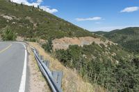 a motorcycle riding up the side of a road next to a grassy hillside under blue skies