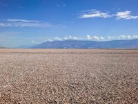 the man is riding his motorcycle on the desert landscape, in the middle of the distance is the mountain range