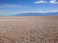 the man is riding his motorcycle on the desert landscape, in the middle of the distance is the mountain range