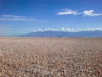 the man is riding his motorcycle on the desert landscape, in the middle of the distance is the mountain range