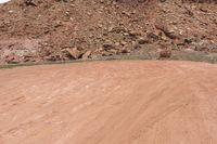 a person rides a yellow motorcycle down a dirt road next to a mountain of rocks