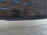 a person riding a motorcycle down the street in motion, with blurry buildings and trees in the background