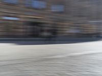 a person riding a motorcycle down the street in motion, with blurry buildings and trees in the background