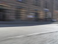 a person riding a motorcycle down the street in motion, with blurry buildings and trees in the background