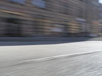 a person riding a motorcycle down the street in motion, with blurry buildings and trees in the background