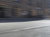 a person riding a motorcycle down the street in motion, with blurry buildings and trees in the background