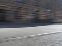 a person riding a motorcycle down the street in motion, with blurry buildings and trees in the background