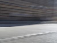 a person riding a motorcycle down the street in motion, with blurry buildings and trees in the background