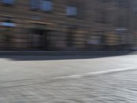 a person riding a motorcycle down the street in motion, with blurry buildings and trees in the background