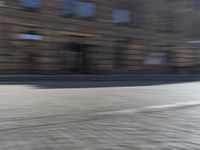 a person riding a motorcycle down the street in motion, with blurry buildings and trees in the background