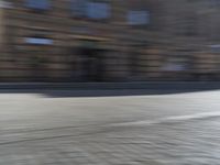 a person riding a motorcycle down the street in motion, with blurry buildings and trees in the background