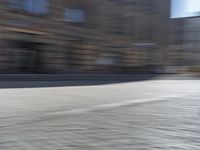 a person riding a motorcycle down the street in motion, with blurry buildings and trees in the background