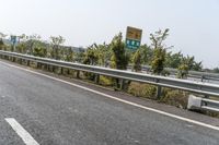 a man riding a motorcycle down the middle of highway side road next to trees and sky