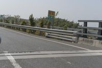 a man riding a motorcycle down the middle of highway side road next to trees and sky