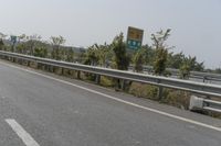 a man riding a motorcycle down the middle of highway side road next to trees and sky