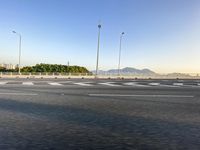 a white motorcycle is riding through a street next to the water with mountains in the background