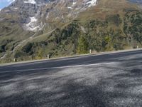 a person rides a motorcycle on the road near a mountain side and the camera is out