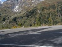 a person rides a motorcycle on the road near a mountain side and the camera is out