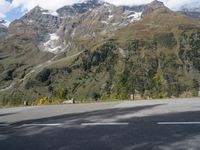 a person rides a motorcycle on the road near a mountain side and the camera is out