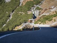 a man is riding his motorcycle down a mountain road with green trees in the background
