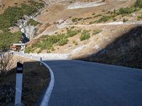 a man is riding his motorcycle down a mountain road with green trees in the background