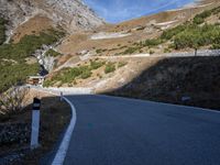 a man is riding his motorcycle down a mountain road with green trees in the background