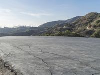 a motorcycle riding in the middle of a empty area with mountains in the distance nearby