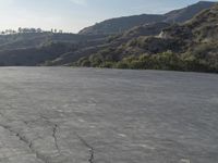 a motorcycle riding in the middle of a empty area with mountains in the distance nearby