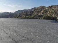 a motorcycle riding in the middle of a empty area with mountains in the distance nearby
