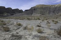 a person riding their motorcycle on a dirt road with many rocks in the background with mountains in the background