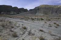 a person riding their motorcycle on a dirt road with many rocks in the background with mountains in the background
