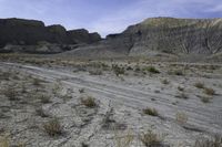 a person riding their motorcycle on a dirt road with many rocks in the background with mountains in the background