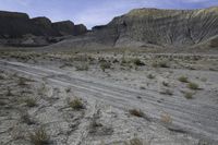 a person riding their motorcycle on a dirt road with many rocks in the background with mountains in the background