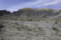 a person riding their motorcycle on a dirt road with many rocks in the background with mountains in the background