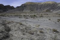 a person riding their motorcycle on a dirt road with many rocks in the background with mountains in the background