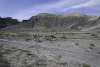 a person riding their motorcycle on a dirt road with many rocks in the background with mountains in the background