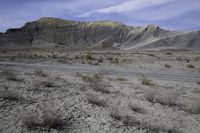 a person riding their motorcycle on a dirt road with many rocks in the background with mountains in the background