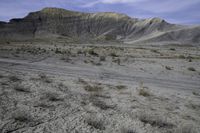 a person riding their motorcycle on a dirt road with many rocks in the background with mountains in the background