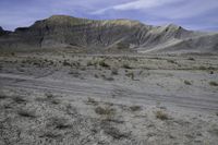 a person riding their motorcycle on a dirt road with many rocks in the background with mountains in the background