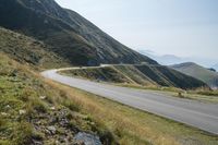 a motorcycle parked on a small mountain side road near mountains with no cars driving on it