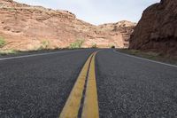 a person riding a motorcycle along a narrow road through rocks and sand cliffs a grassy area on both sides