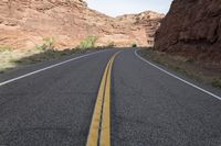 a person riding a motorcycle along a narrow road through rocks and sand cliffs a grassy area on both sides