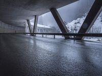 a motorcycle is going down the highway in the snow, under a bridge that goes above it