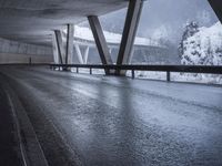 a motorcycle is going down the highway in the snow, under a bridge that goes above it